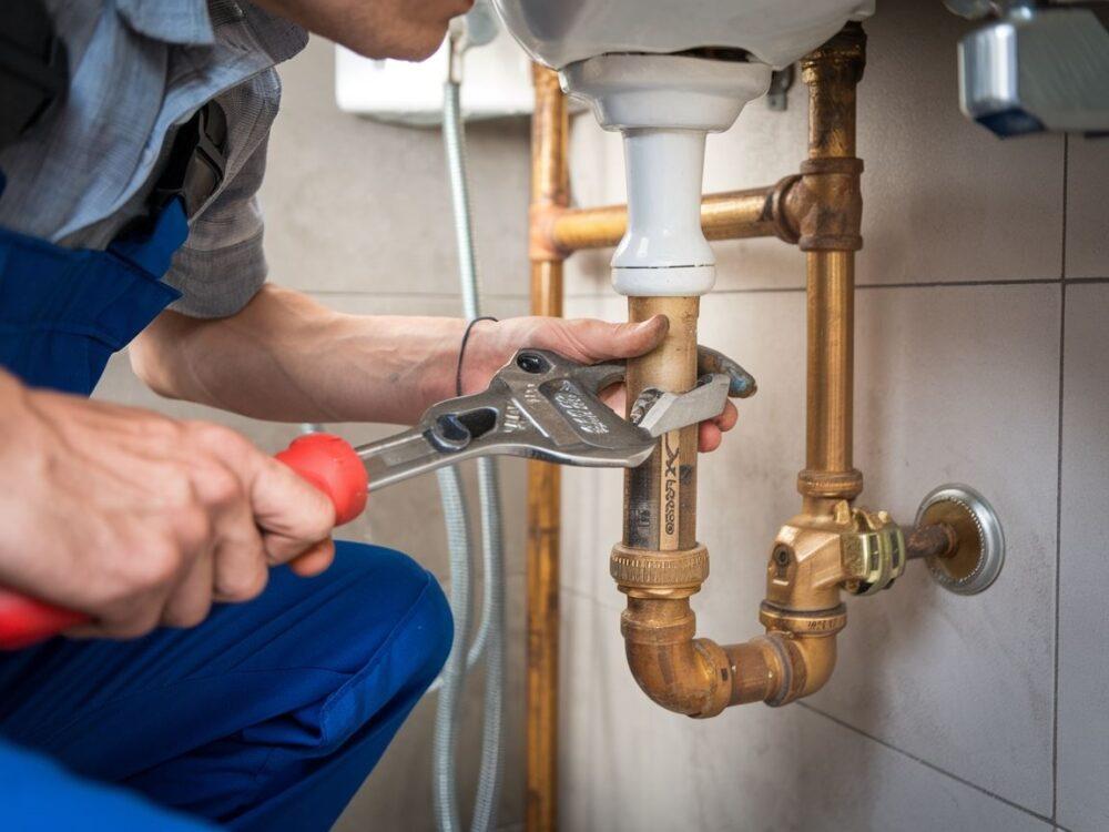 Hydraulik naprawiający rurę w ścianie